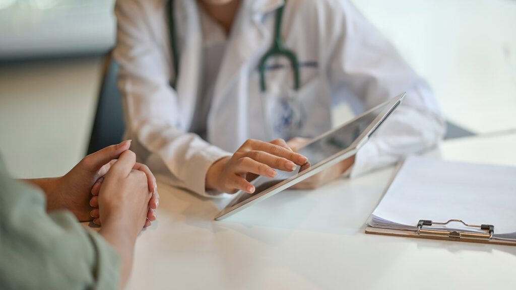 A doctor going over the results of a test with a patient on their tablet.