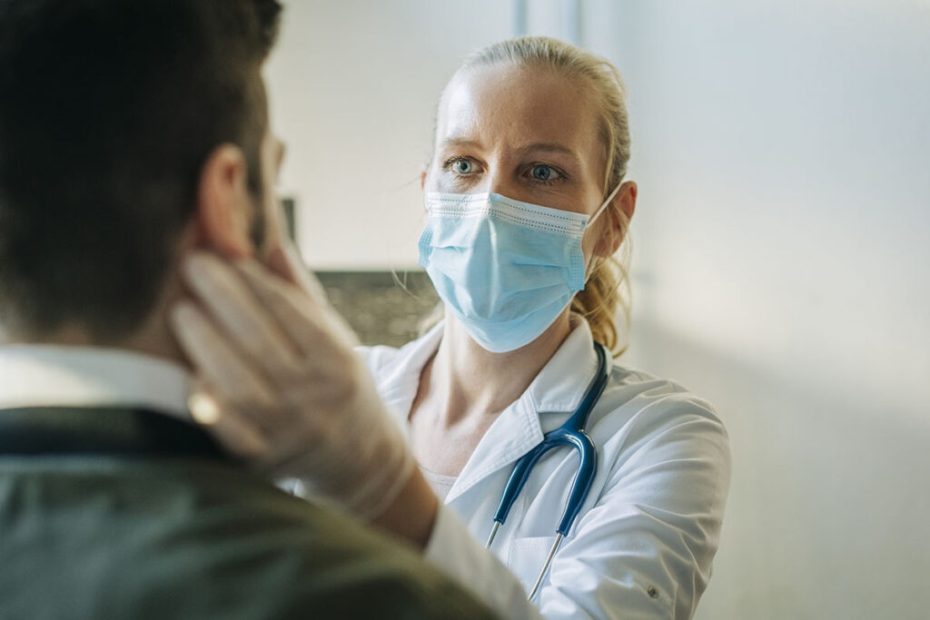 A doctor wearing surgical mask while examining their patient.