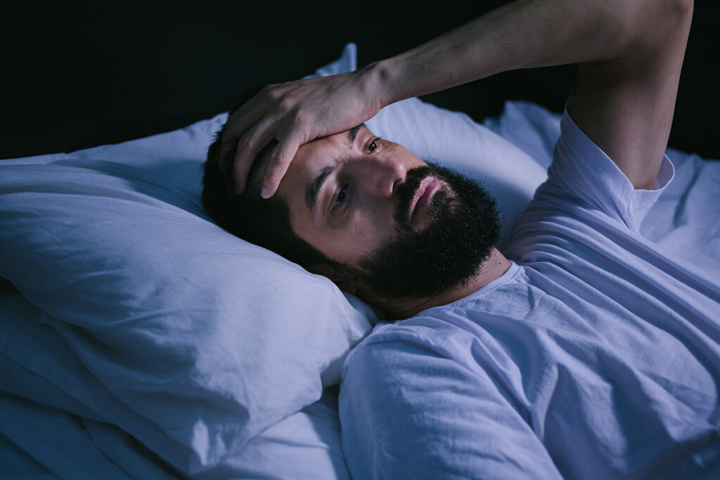 Young man in bed with eyes opened suffering insomnia and sleep disorder.